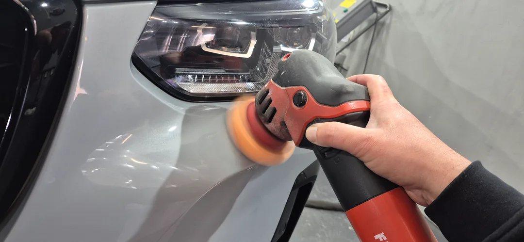 Machine polisher being used on BMW X4 front bumper during single stage polish